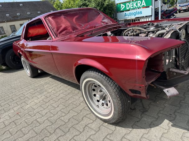 Rot lackierter Ford Mustang mit abgedeckter Frontscheibenöffnung und ausgebauten Anbauteilen