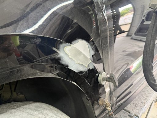 Angeschliffene Reparaturstelle mit freigelegtem Blech am Kotflügel
