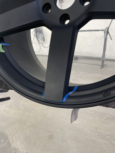 Abkleben der Speichen Detail einer dunklen Felgenspeiche mit blauem Konturenband