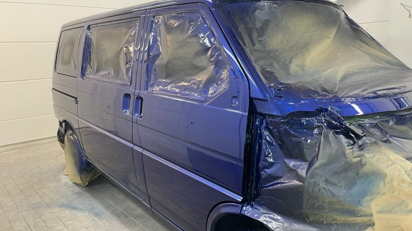 Blau lackierte Seitenpartie des VW T4 mit noch abgedeckten Scheiben