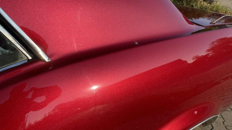 Nahaufnahme der roten Mustang-Lackierung mit feinen Glanzeffekten im Sonnenlicht