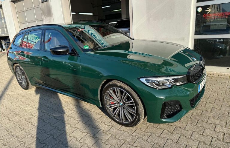 Fahrzeugaufbereitung Grüner BMW Touring mit glänzendem Lack vor der Werkstatt