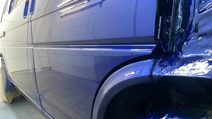 Detail der glänzenden Seitenfläche und des Radlaufs eines VW T4 in BMW San Marino Blau